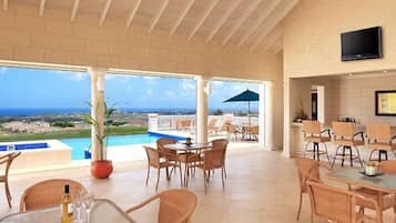 Relax in this spacious area with a high ceiling, featuring a large patio with ocean views and a swimming pool.