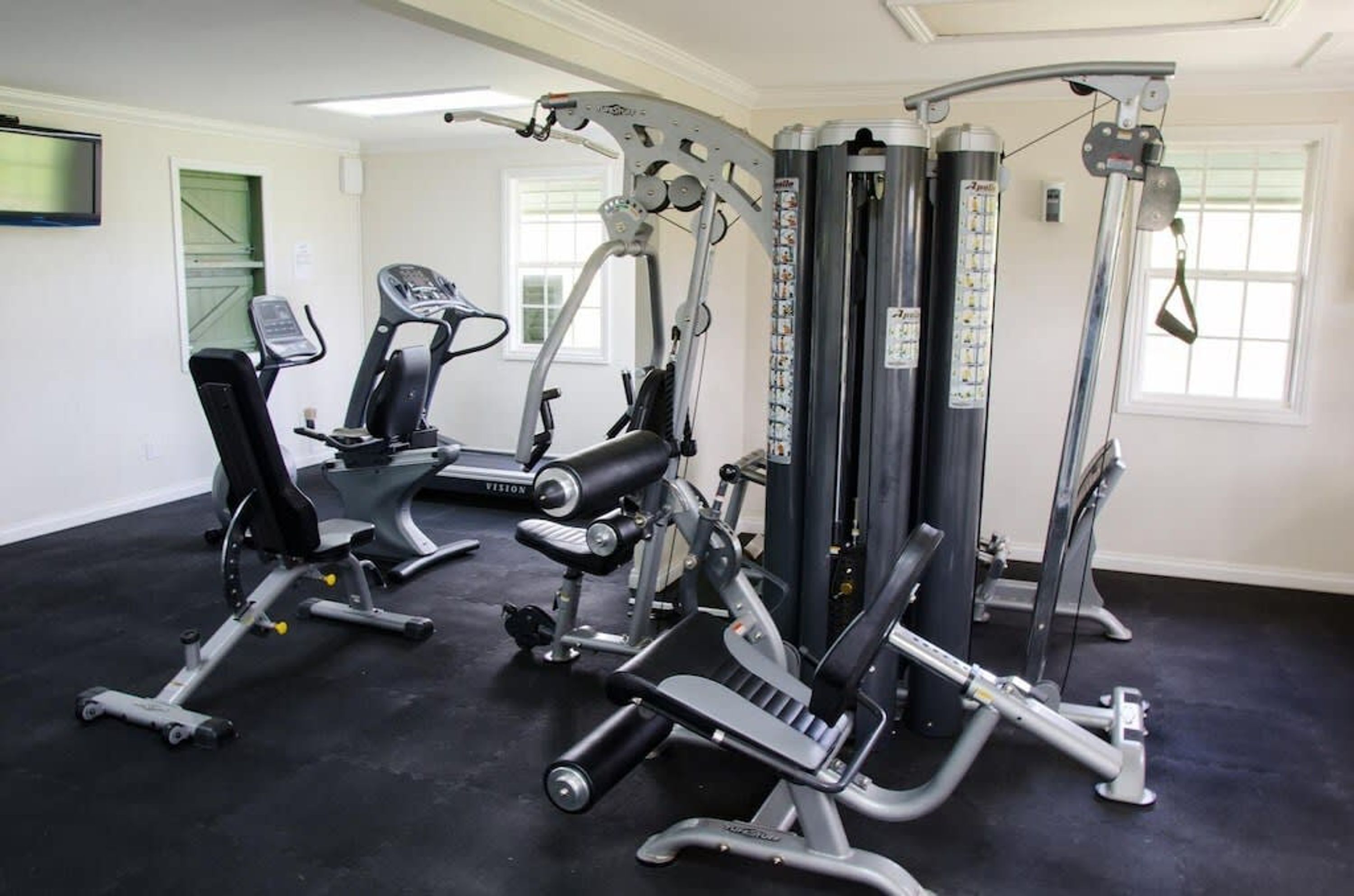 A gym with various exercise machines, including a bench press, a leg press, and a cable machine.