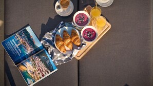 Una bandeja de desayuno con croissants, una cazuela de compota de bayas y dos tazas de café sobre una mesa.