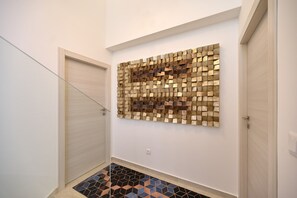 Ein Korridor mit gefliestem Boden, einem an der Wand befestigten Mosaikbild und einer Tür.