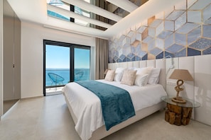 A modern hotel room with a large bed, a glass coffee table, and a view of the sea. - Villa Sunset - Luxury Adriatic Sea View Estate (Podstrana)