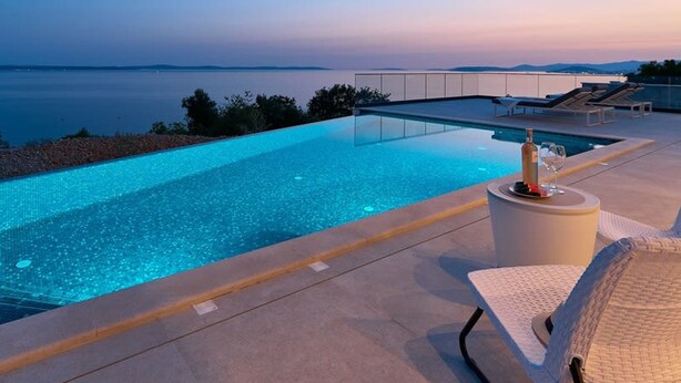 A rooftop infinity pool with a clear view of the sea, lounge chairs, and a table with a bottle and glass. - Villa Sunset - Luxury Adriatic Sea View Estate (Podstrana)