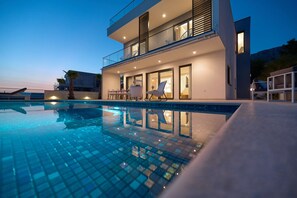Un edificio moderno de dos pisos con una piscina delantera.