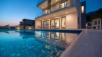 A modern two-story building with a swimming pool in front.