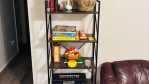Une bibliothèque avec des livres, une plante et une boîte de jeu.
