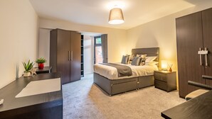 A modern bedroom with a bed, bedside tables, a desk, and a wardrobe. - Garden View - sleeps 6 guests  in 2 bedrooms (York)