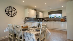A modern kitchen with white cabinets, a marble-tiled backsplash, and a clock on the wall. - Garden View - sleeps 6 guests  in 2 bedrooms (York)