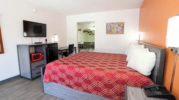 Una habitación de hotel con una cama, un escritorio con computadora, un televisor, un microondas y un teléfono.