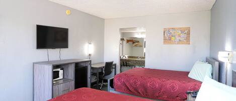 A hotel room with two beds, a desk, a TV, and a map on the wall.