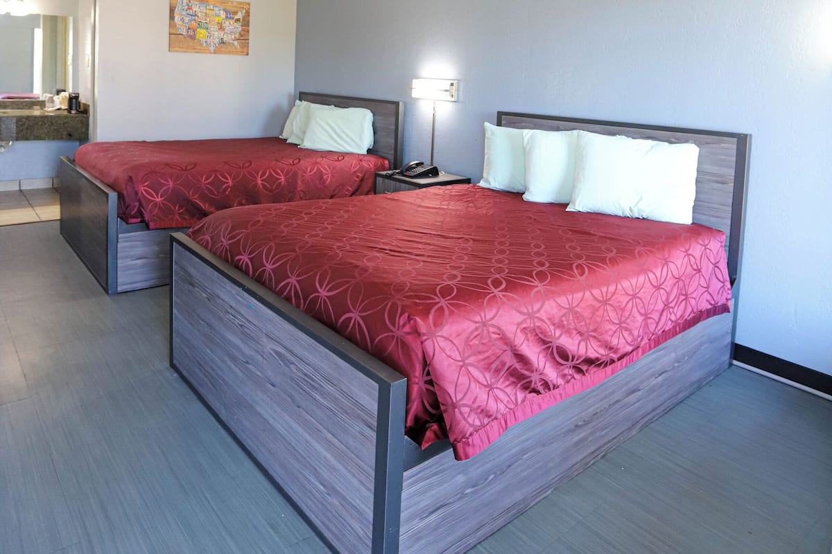 Una cama doble con una colcha roja en una habitación de hotel.