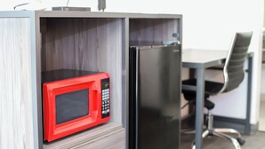 A compact kitchenette with a red microwave and a black refrigerator. - Express Inn  (Durant)