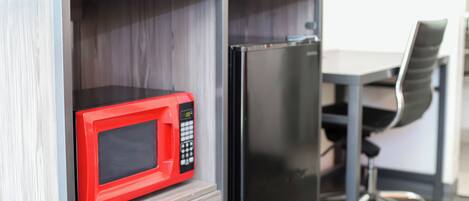 A compact kitchenette with a red microwave and a black refrigerator.