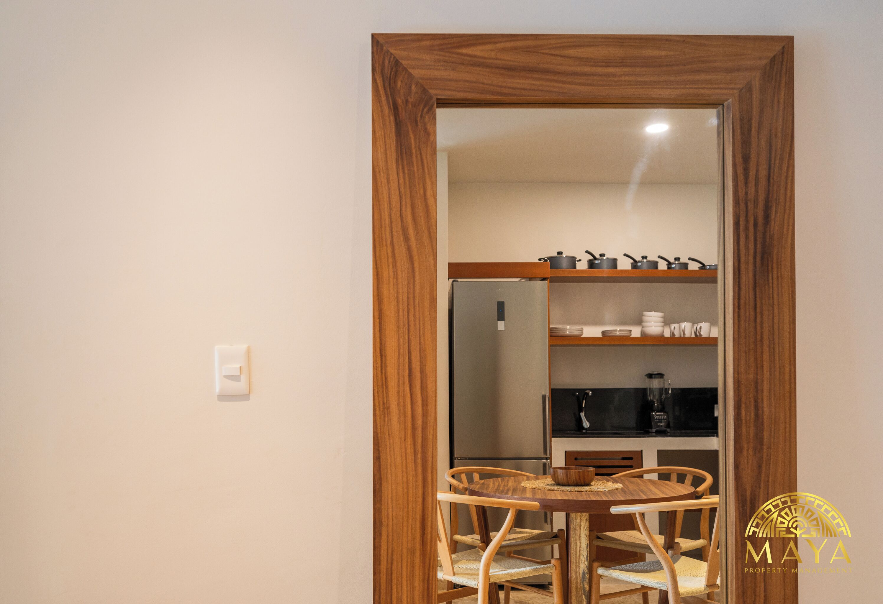 A wooden-framed doorway leading to a kitchen with a refrigerator, stove, and various kitchenware.