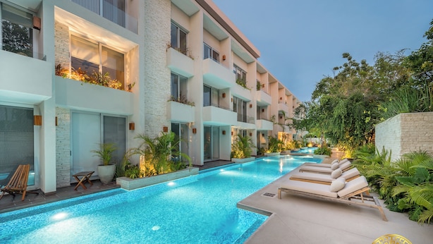 A modern hotel with a swimming pool, outdoor seating, and lush greenery. - NHOA TULUM APARTHOTEL by Maya PM (Tulum)