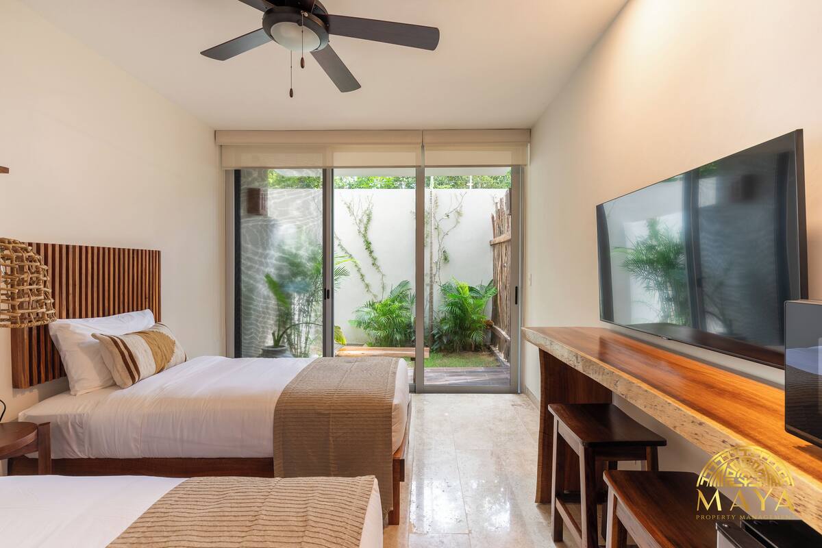 Quarto moderno com cama, escrivaninha e televisão.