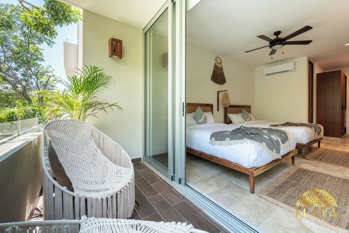 A bedroom with a bed, a ceiling fan, and a sliding glass door leading to an outdoor area with a wicker chair.