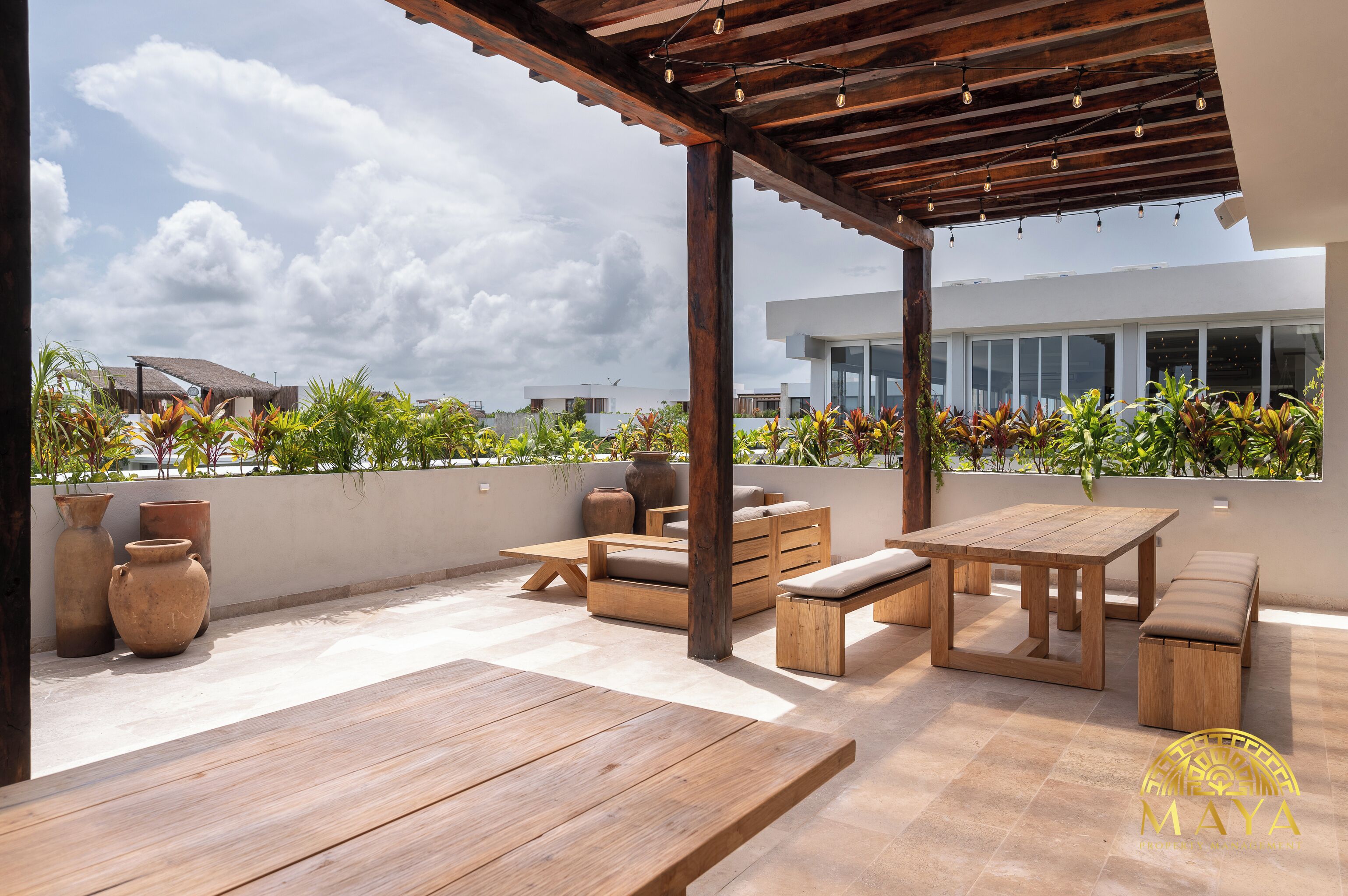 Une terrasse extérieure avec des meubles en bois, une pergola et des plantes en pot.