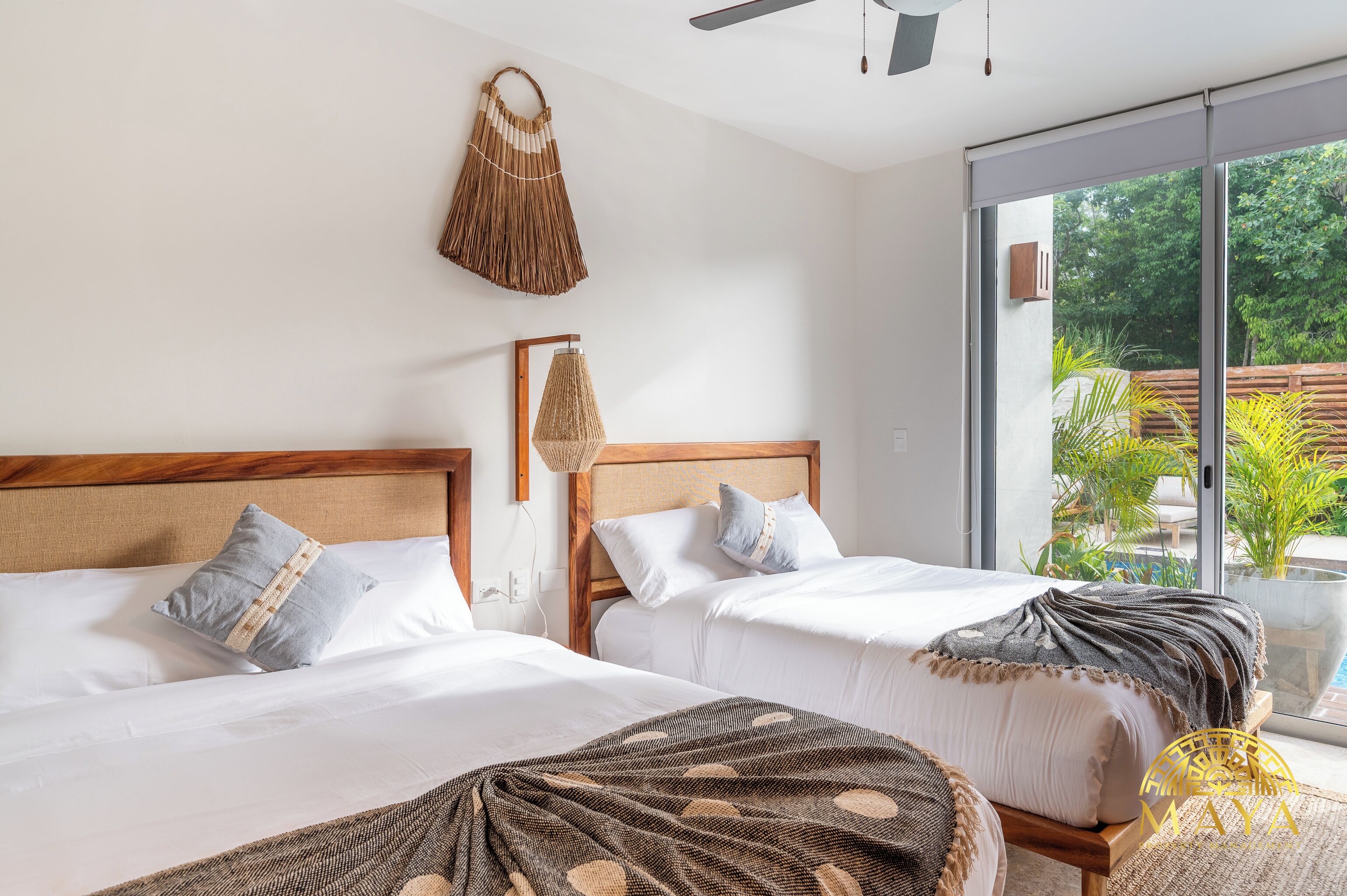 A hotel room with two beds, a large window, and a ceiling fan.