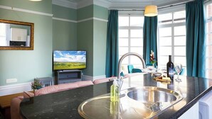 A modern kitchen with a large island, stainless steel sink, and a flat-screen TV. - This apartment is a 2 bedroom(s), 1 bathrooms, located in Scarborough, North Yorkshire. (Scarborough)