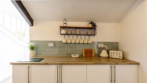 Una cocina con encimera de madera, armarios blancos, un hervidor colgante y un tostador.