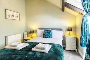 Une chambre d’hôtel avec un lit, deux tables de chevet avec des lampes, une fenêtre avec des rideaux et un tableau encadré au mur.