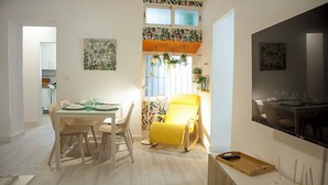 A modern dining area with a table set for four, a yellow chair, and a TV mounted on the wall. - Apartment in the center of Sanlúcar (Sanlúcar de Barrameda)
