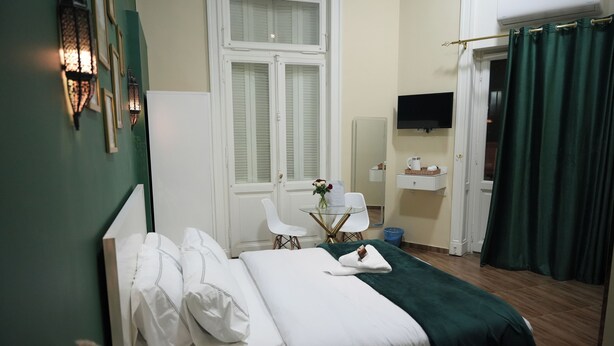 A neatly arranged bedroom with a bed, bedside table, and a small sitting area with a table and chairs. - Hathor House (Cairo)