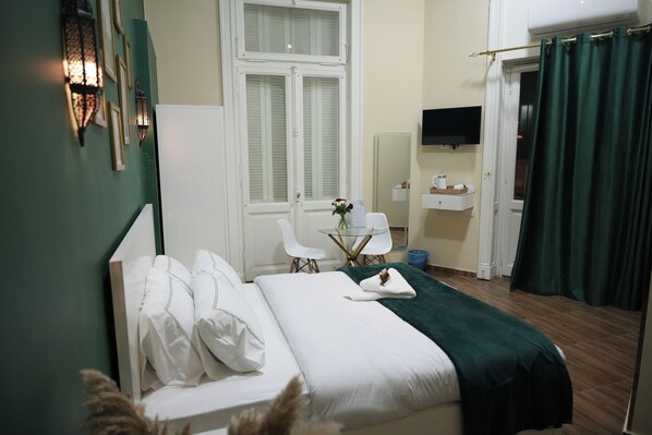 A neatly arranged bedroom with a bed, bedside table, and a small sitting area with a table and chairs. - Hathor House (Cairo)