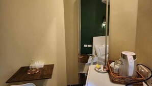 A compact hotel room with a small dining table, a white chair, a mirror, a coffee maker, and a wooden tray. - Hathor House (Cairo)