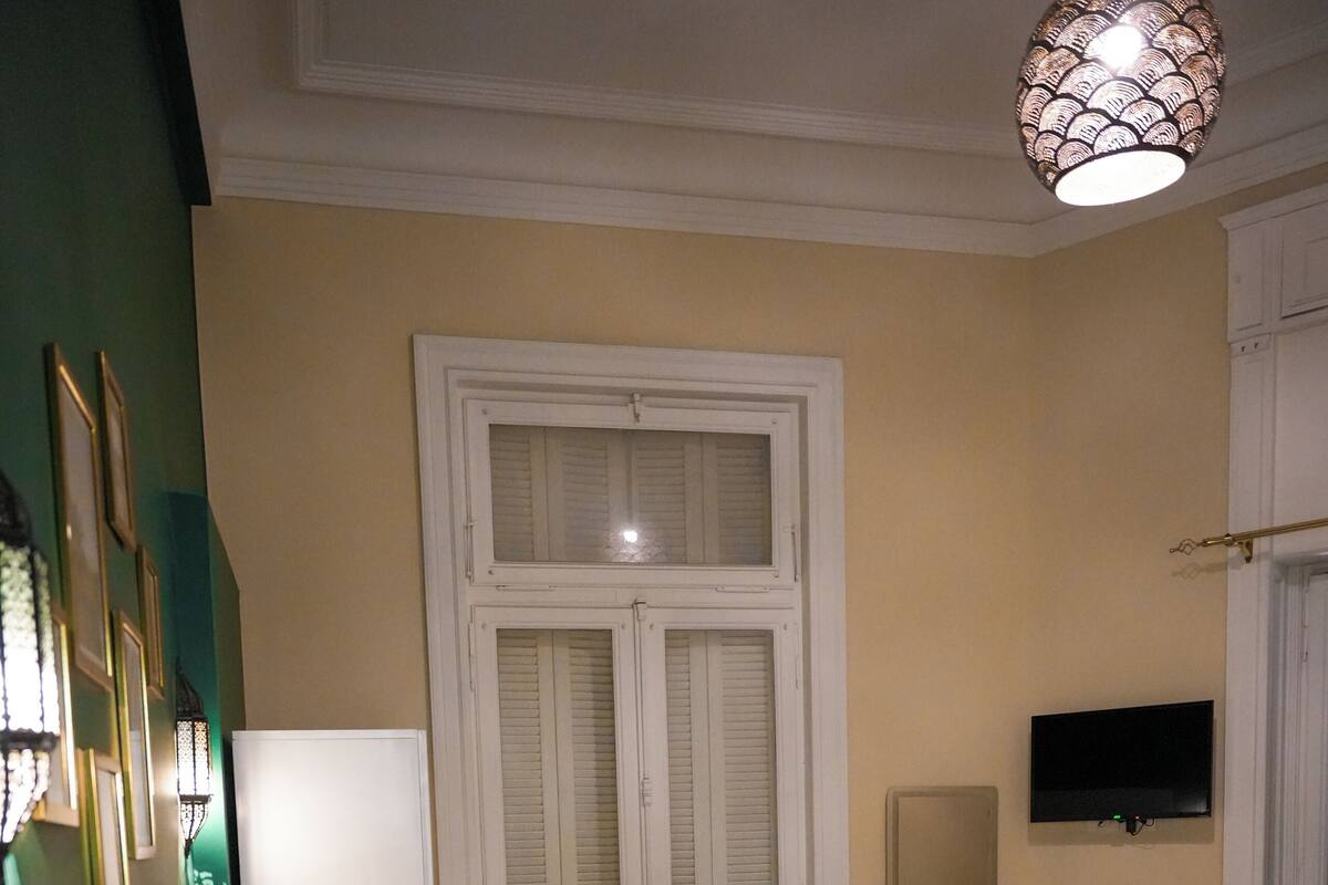 Una habitación de hotel con una cama, una mesita con sillas, un televisor y un espejo.