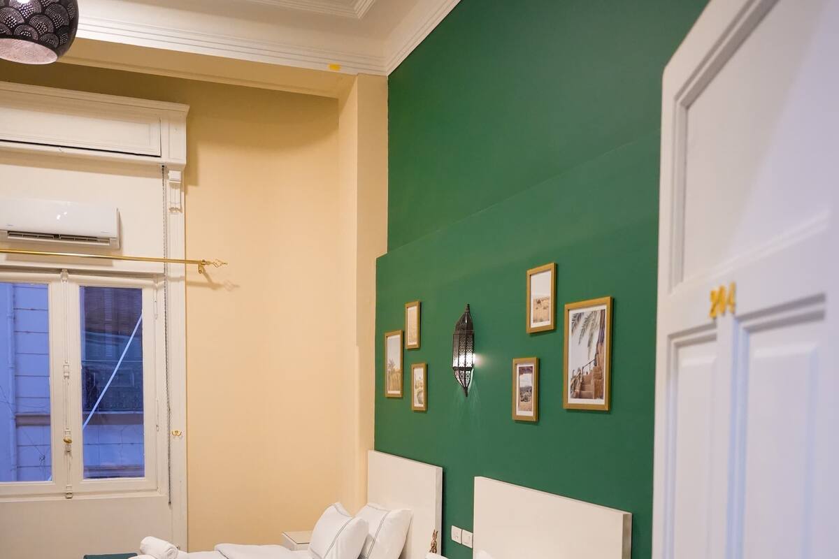 Una habitación de hotel con una cama grande, una mesita de noche y una pared verde decorativa.