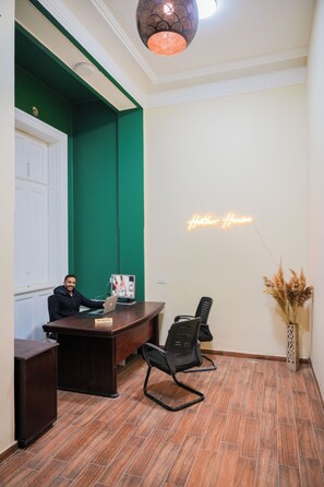 A reception area with a desk, chairs, a computer, and a neon sign. - Hathor House (Cairo)