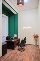 Aula, jossa on vastaanottotiski, tuoleja, tietokone ja neonvalomainos.