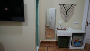 A room with a flat-screen TV, a mirror, a sink, a trash bin, and a mini-fridge. - Hathor House (Cairo)
