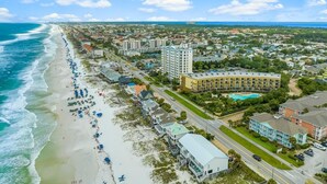 An aerial view of a coastal town with a beachfront, hotels, and a road running parallel to the beach. - Stunning Newly Renovated Poolside Condo Near Beach. Now With Beach Service! (Miramar Beach)