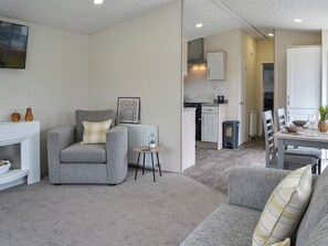 A modern living room with a grey sofa, a small round table, and a kitchen in the background.