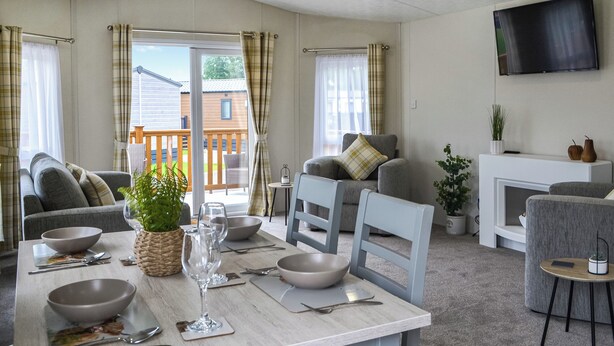 A modern living room with a dining area, a fireplace, and a television mounted on the wall. - 2 bedroom accommodation in Carnaby, near Bridlington (Carnaby, near Bridlington)