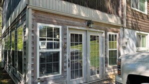 Un edificio de madera con puerta de garaje, buzón y contenedor de basura.