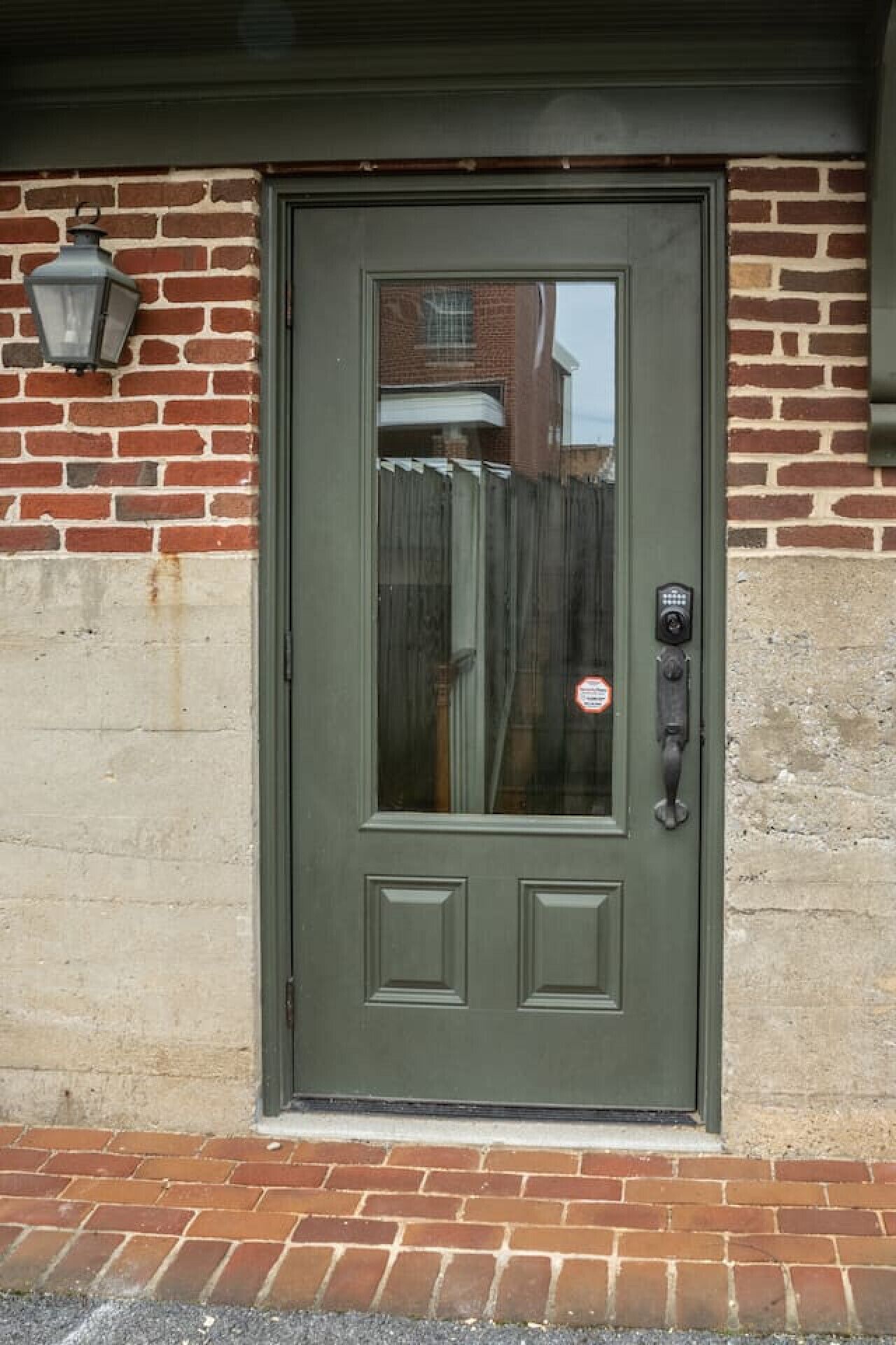 A green door with a window, a keypad lock, and a mailbox on the wall.