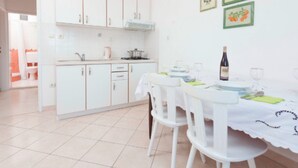 A bright kitchen with white cabinets and a dining area with a table set for two. - Apartments Lili Two Bedroom Apartment Sea View (Podgora)