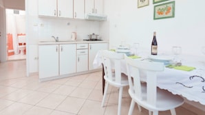 A bright kitchen with white cabinets and a dining area with a table set for two. - Apartments Lili Two Bedroom Apartment Sea View 3 (Podgora)