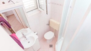 Een kleine badkamer met een wastafel, toilet en douche.