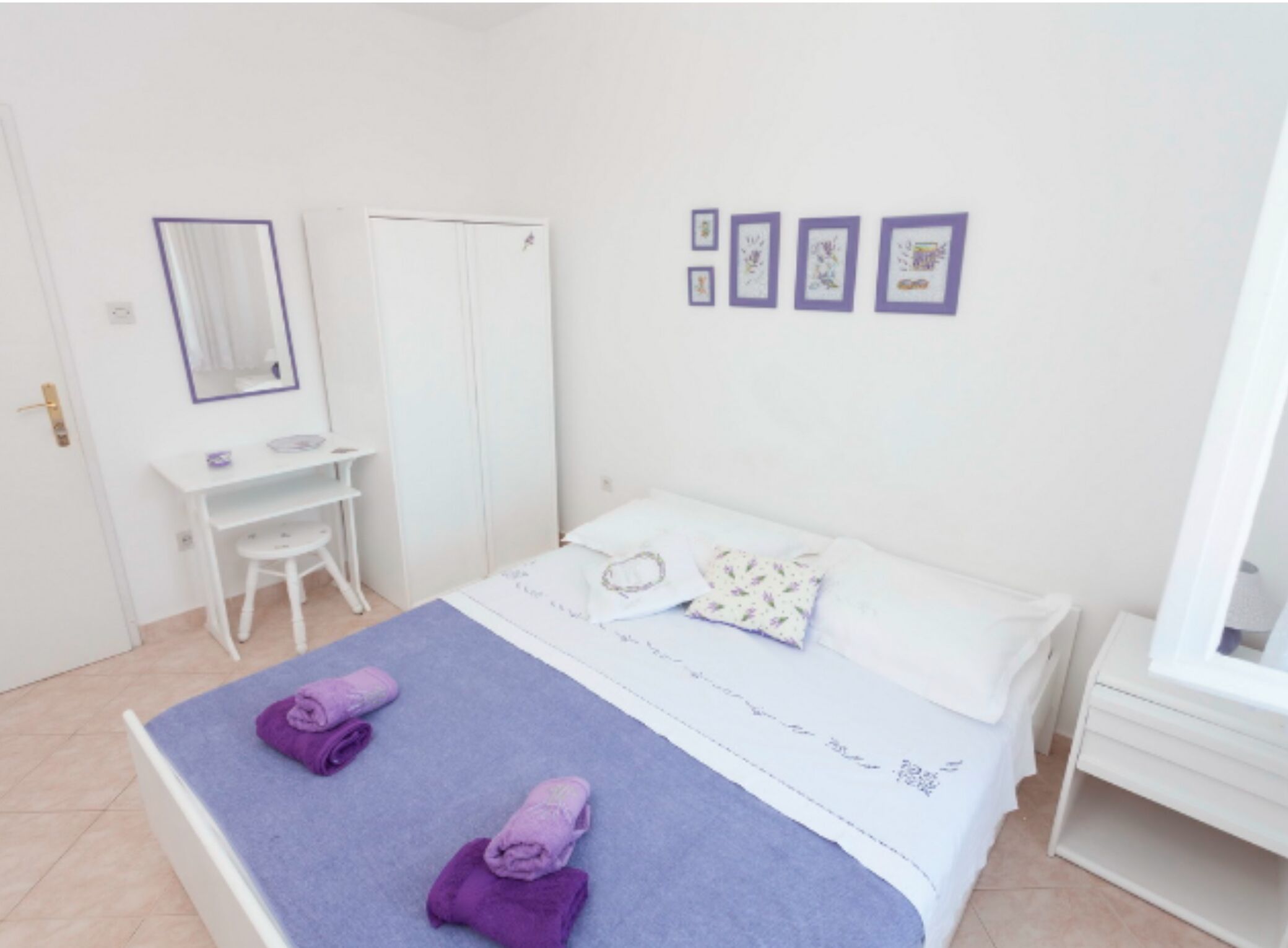 A bedroom with a bed, a desk, a chair, a wardrobe, and a window.