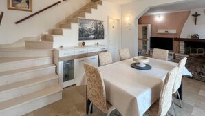 A dining area with a table set for six, a staircase, a kitchen area, and a fireplace. - Holiday Home Aurora - Three bedroom Holiday Home (Postira)