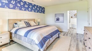 A bedroom with a bed, nightstands, a dresser, a ceiling fan, and a wall with a sailboat pattern. - Walk to Marina: Pet-Friendly Little River Home! (Little River)