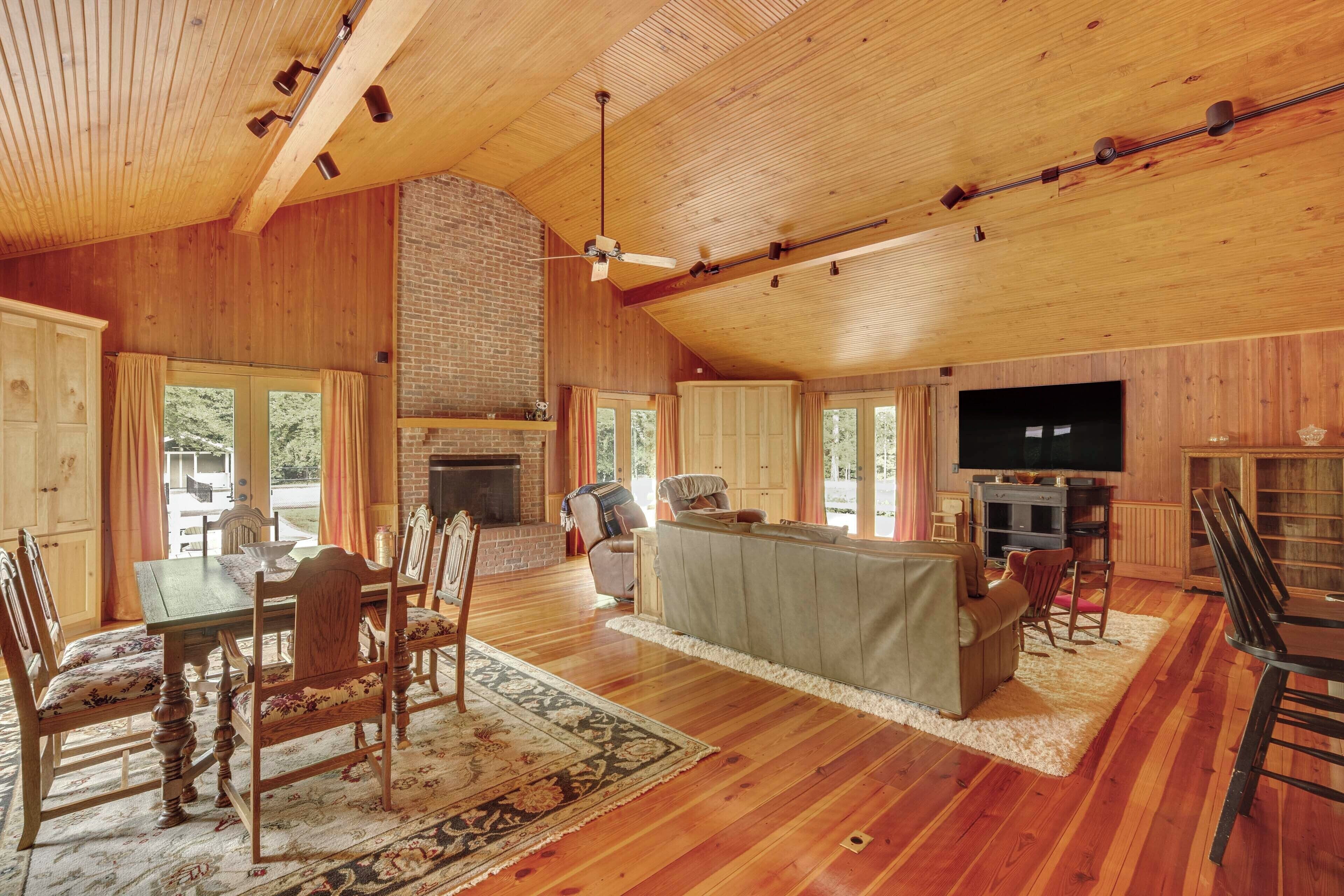 Ein geräumiges Wohnzimmer mit Holzboden, einem Kamin, einem Fernseher und einem Essbereich mit Tisch und Stühlen.