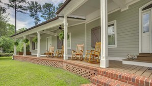 Ein Haus mit einer Veranda, Ziegelstufen und Holzschaukelstühlen.