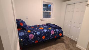 A small bedroom with a bed, a window, and a closet.