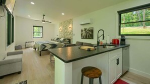 Una cucina moderna con isola centrale, un'area pranzo con divano, un letto e vista sull'esterno.