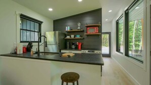 A modern kitchen with a central island, a refrigerator, a microwave, and a coffee maker. - Afternoon Delight cabin at Trickle Creek (Logan)
